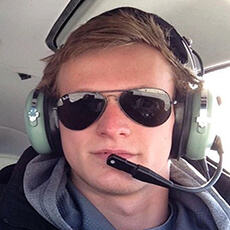 Amerlink student Filip, equipped with headphones and microphone, wearing dark sunglasses inside a helicopter, embodying adventure and exploration