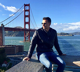 Amerlink student Piotr, looking thoughtful in a leather jacket, with the iconic San Francisco bridge in the background