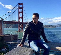 Amerlink student Piotr, looking thoughtful in a leather jacket, with the iconic San Francisco bridge in the background